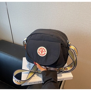 Detail of black camera bag with red logo and colorful patterned wide fabric strap