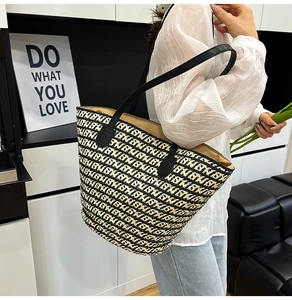 Dettaglio della borsa tote in paglia intrecciata con spalline in finta pelle nera