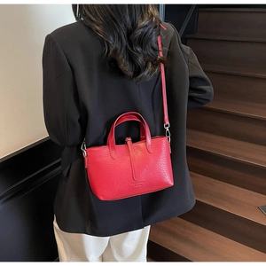 Model wearing a red crocodile embossed leather crossbody handbag on a wooden staircase