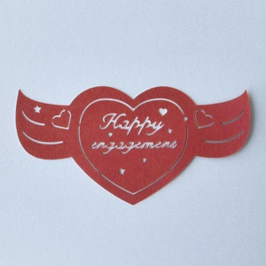 Vue détaillée du carton rouge en forme de cœur ailé avec découpe Happy Engagement