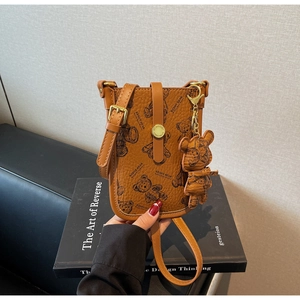 Close-up of brown pebbled leather phone bag featuring black printed bear patterns