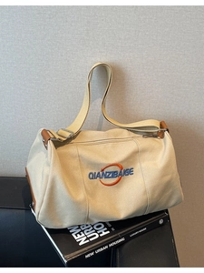 Sac fourre-tout en toile beige avec finitions en cuir et bandoulière sur un banc