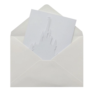 Close-up of white laser-cut castle wedding invitation with intricate paper spires