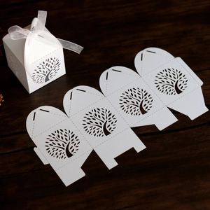 Detail of laser-cut tree design on white wedding favor box with organza ribbon bow