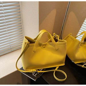 Detail of yellow lychee grain leather tote bag showing twin handles and shoulder strap
