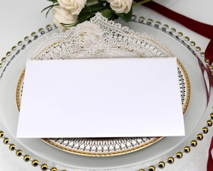 Detail of laser-cut lace wedding invitation on elegant porcelain with white roses