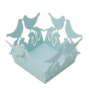 Close-up of laser-cut light blue cupcake wrappers with hollow bird and floral patterns