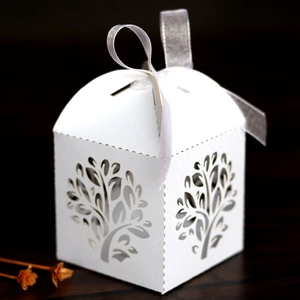 Detail of laser-cut tree design on white pearlescent candy gift box with ribbon bow