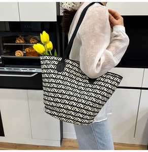 Dettaglio di una borsa tote in tessuto geometrico bianco e nero con manici in pelle rifiniti