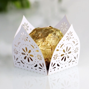 Detail of white laser-cut candy box with delicate floral lace pattern and gold chocolate