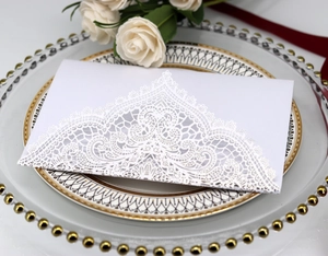 Detail of laser-cut lace pattern on elegant wedding invitation card with floral decor