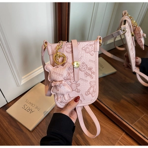 Detailed macro view of pink crossbody phone bag with embossed teddy bear patterns and charm