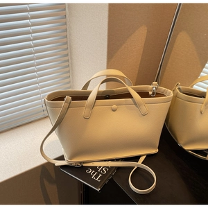 Detail of beige lychee textured leather tote with magnetic buckle and adjustable strap