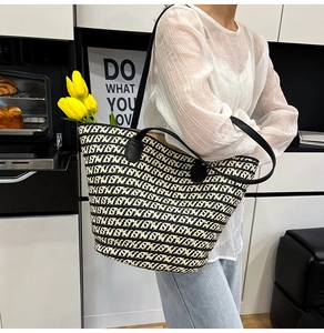Dettaglio della borsa tote intrecciata con manici in pelle nera e trama geometrica