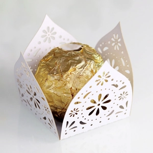 Macro view of white laser-cut hollow lace favor box with gold foil chocolate detail