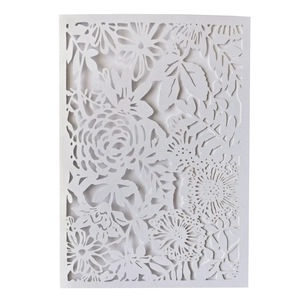 Close-up of laser-cut white wedding invitation with floral rose and leaf hollow patterns