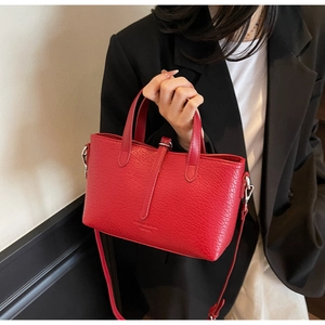 Detail of red textured leather crossbody bag with silver hardware and fashion logo