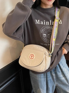 Beige crescent crossbody bag with purple patterned strap shown on model for daily commute