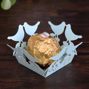 Detail of light blue laser-cut bird pattern favor box with a gold foil chocolate ball