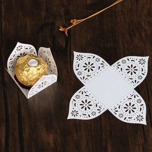 Detail of laser-cut wedding candy box with floral patterns on dark wood table