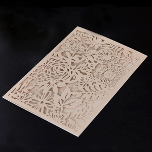 Detail of laser-cut rose and sunflower motifs on beige paper wedding invitation card