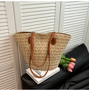 Dettaglio della borsa tote in paglia intrecciata con motivi geometrici e manici marroni