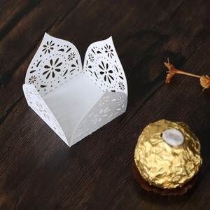Macro detail of laser-cut white paper cupcake wrapper with floral pattern for weddings