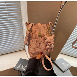 Close-up of pink lychee leather crossbody bag with teddy bear print and golden buckle
