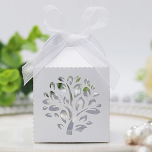 Detail of laser-cut tree design on white pearlescent paper candy box with ribbon bow
