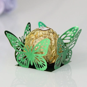 Close-up of laser-cut green butterfly chocolate wrappers with a metallic pearl finish