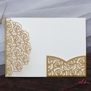 Detail of laser-cut rose patterns with gold glitter finish on a wedding invitation card