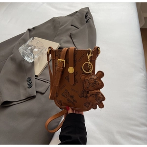 Detailed view of a brown crossbody phone bag featuring teddy bear prints and leather charm