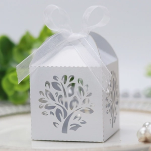 Close-up of white laser-cut Tree of Life candy box with ribbon and delicate patterns