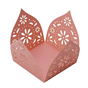 Macro detail of laser-cut pink paper candy box featuring intricate floral lace patterns