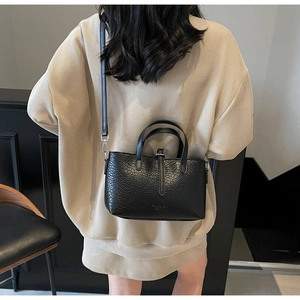 Fashionable black crocodile embossed crossbody bag styled on a beige oversized knit sweater
