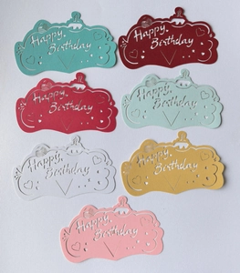 Flat lay of colorful hollow Happy Birthday paper cake toppers in seven vibrant colors