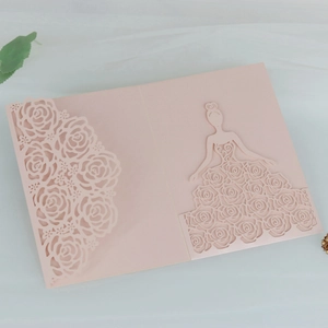 Macro shot of laser cut hollow rose pattern and female silhouette on pink wedding card