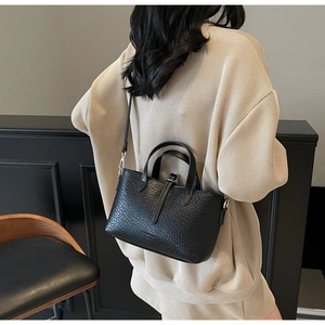 Detail of black crocodile texture handbag with silver hardware and adjustable strap