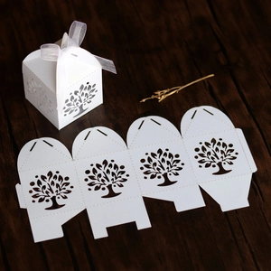 Detailed laser-cut tree design on a white gift box with silk ribbon on wood background