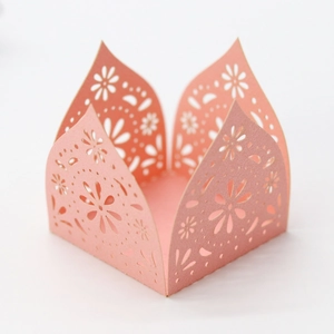 Detail of laser-cut floral cupcake wrapper in coral pink with elegant scalloped edges