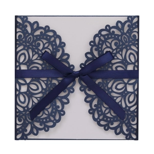 Détail de la découpe laser motif dentelle sur faire-part bleu marine avec nœud en soie