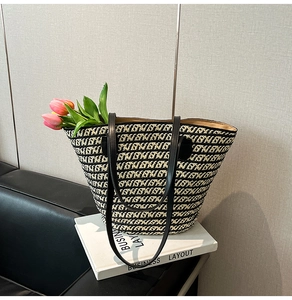 Dettaglio della borsa tote intrecciata con motivi nero e beige e manici in pelle