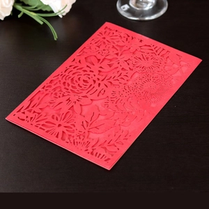 Detail of red laser-cut floral invitation cover featuring intricate rose and leaf patterns