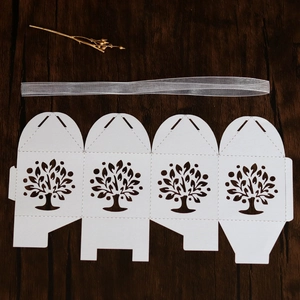 Laser-cut Tree of Life candy boxes with silver ribbons on a rustic wood surface