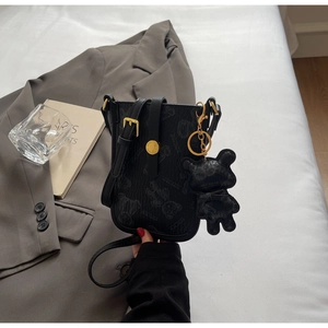 Detail of black teddy bear print crossbody bag with gold hardware and bear charm