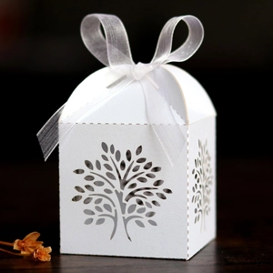 Close-up of laser-cut Tree of Life candy box with white ribbon and elegant hollow design