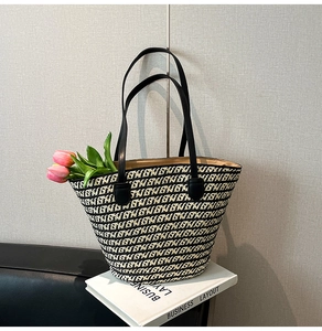 Dettaglio della borsa tote intrecciata a righe con sottili spalline in pelle nera e capienza