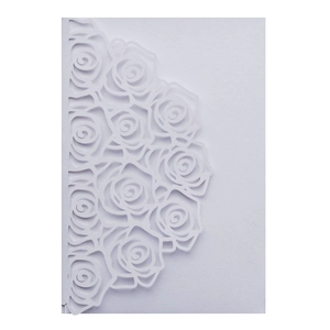 Detail view of white laser-cut rose floral pattern on pearlescent paper invitation cover