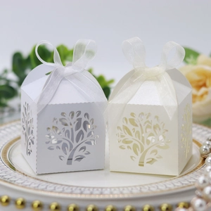 Detailed laser-cut tree design on white and cream party candy boxes with ribbon bow