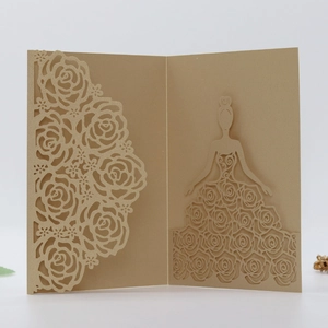 Detail of laser-cut champagne gold wedding invitation with intricate rose patterns